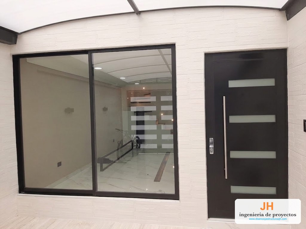 Puerta ventana corrediza 80-25 en aluminio negro de dos hojas junto a puerta batiente 1102 con vidrio esmerilado, casa en Bogotá, obra de JH