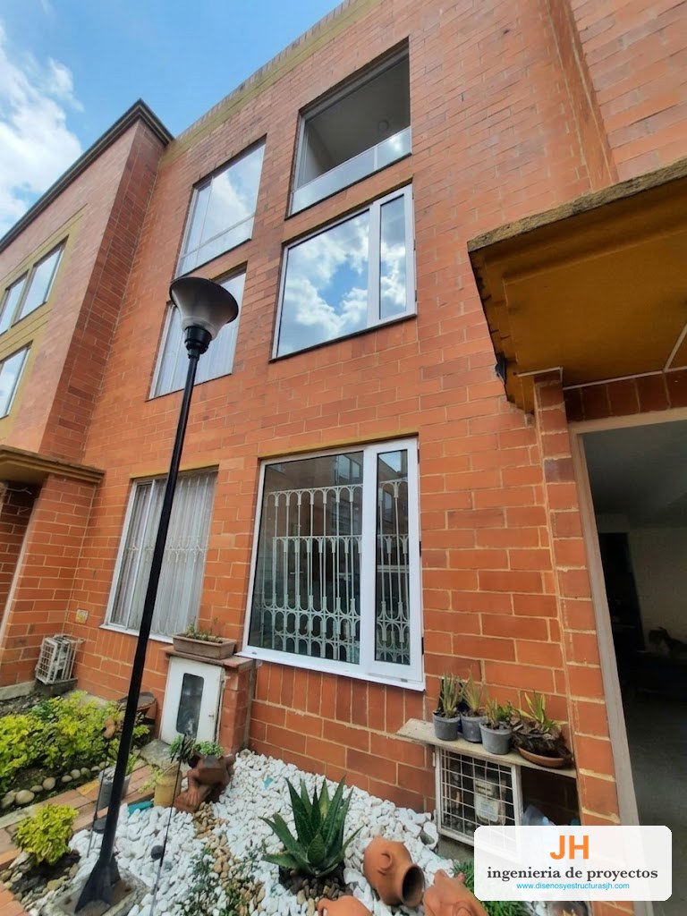 Ventanas antiruido oscilobatientes Zinú en aluminio blanco con doble vidrio, fachada en ladrillo de casa en Bogotá, obra de JH