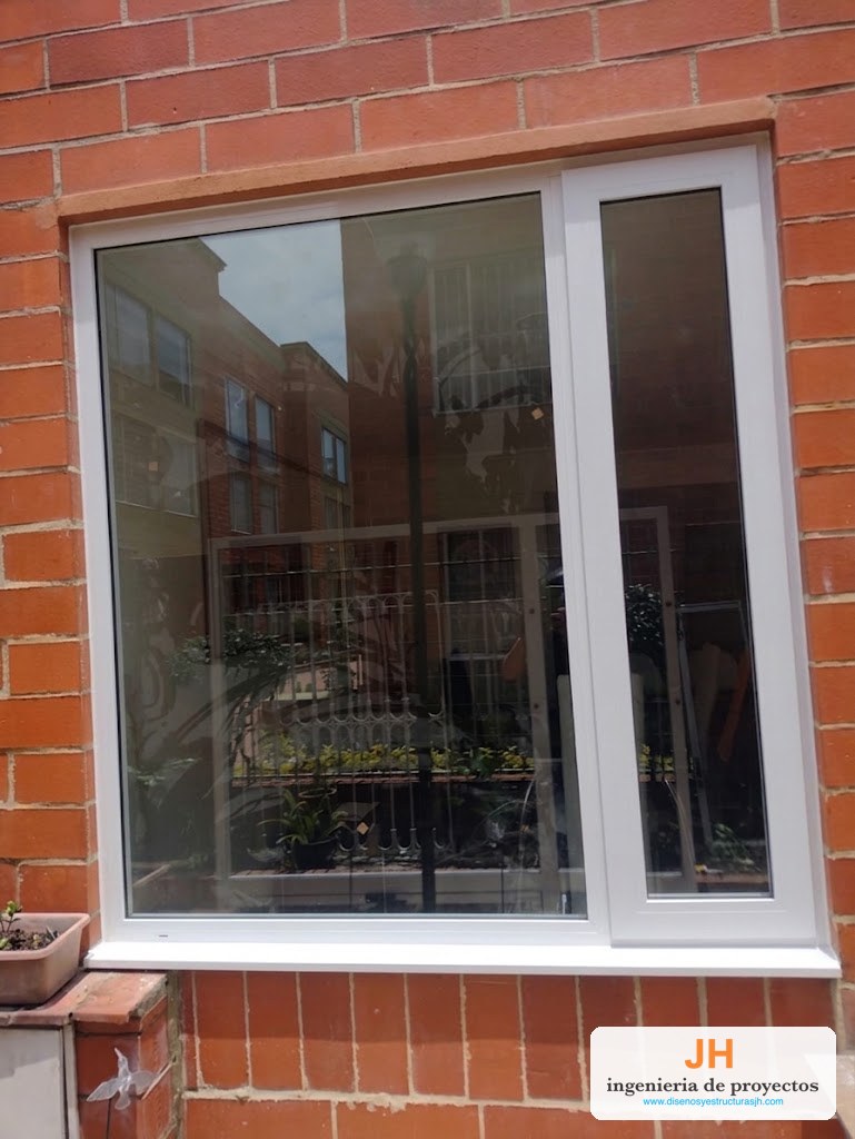 Ventana termoacústica Zinú en aluminio blanco con paño fijo y nave oscilobatiente, doble vidrio hermético, fachada en ladrillo en Bogotá, obra de JH