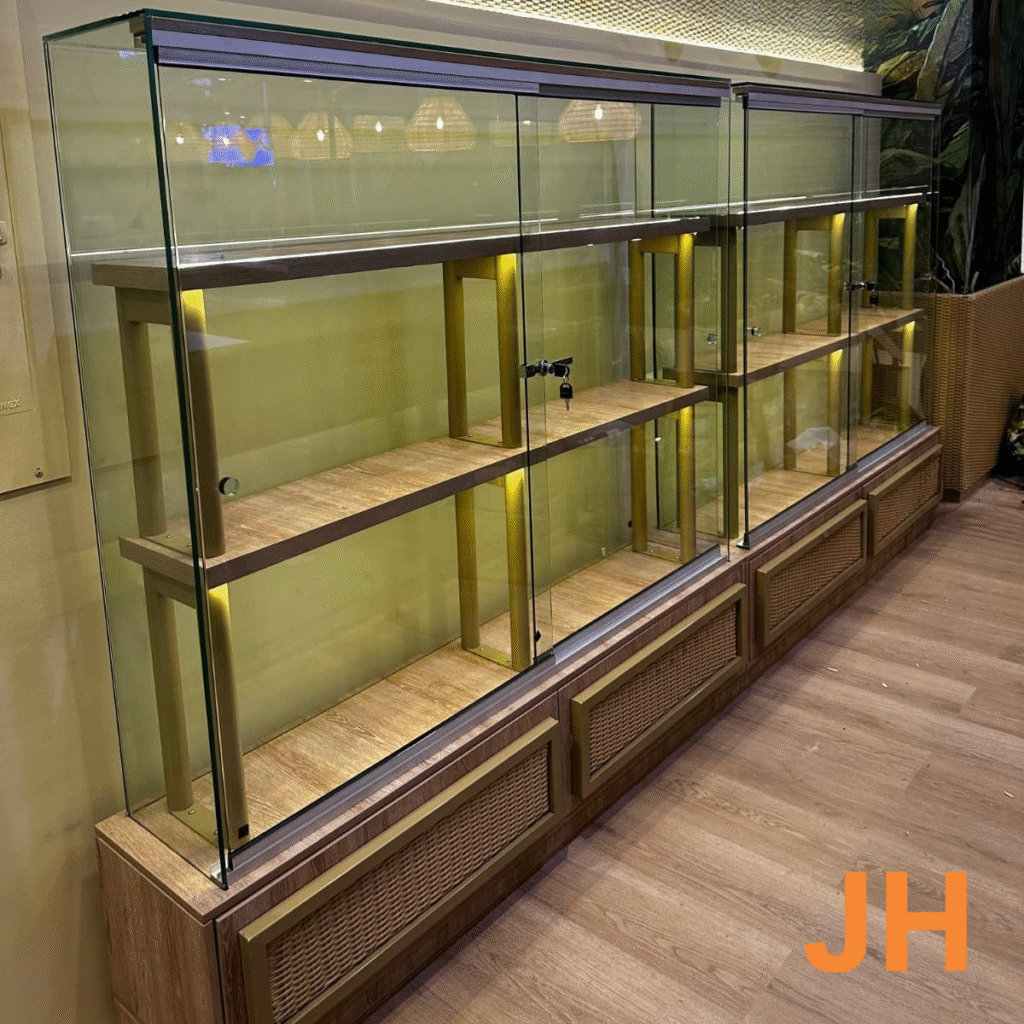 Detalle de vitrina en madera y vidrio con iluminación cálida integrada, diseñada para realzar los productos de exhibición.