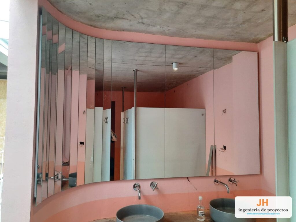 Espejo de pared a la medida en paneles verticales sobre muro curvo, baño de edificio en Bogotá, obra de JH