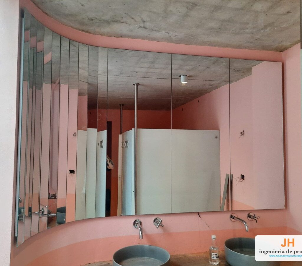 Espejo de pared a la medida en paneles verticales sobre muro curvo, baño de edificio en Bogotá, obra de JH