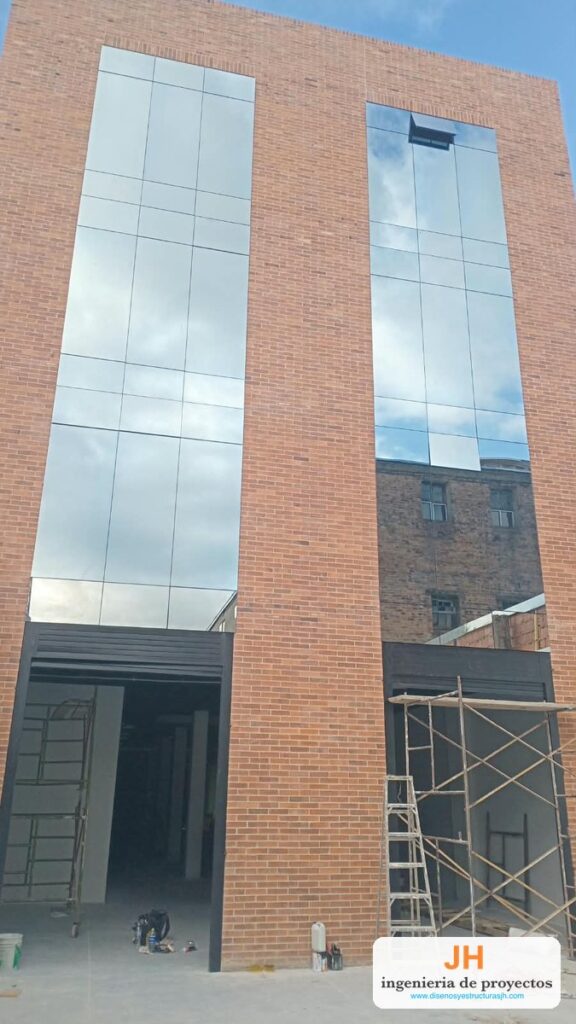 Fachada flotante en aluminio y vidrio reflectivo sobre fachada en ladrillo, sistema nacional instalado por JH en Bogotá