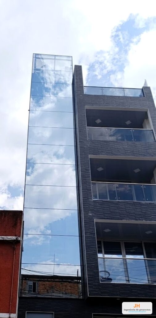 Fachada flotante piel de vidrio reflectivo con sistema nacional, punto fijo de cinco pisos en un edificio de Bogotá, fabricada e instalada por JH